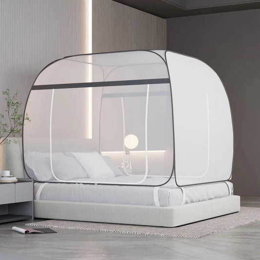 Moustiquaire Lit Carrée innovante facile à installer autour d'un lit avec des coussins et un drap blanc une table de nuit avec une plante verte et un meuble en fond avec une lampe